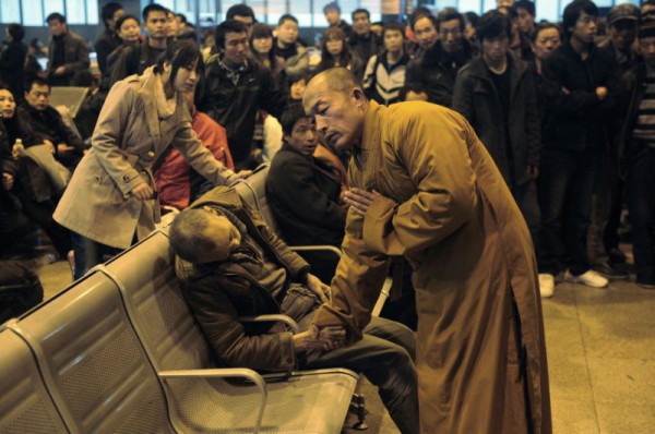 Китай, 2011 год. Буддийский монах проводит обряд над человеком, который умер прямо на железнодорожной станции среди многолюдной толпы.